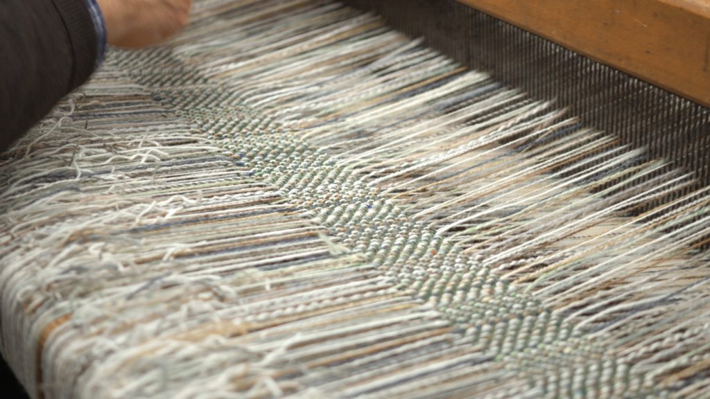A still from the film The Last of the Handweavers. A close up shot of a weaving machine.